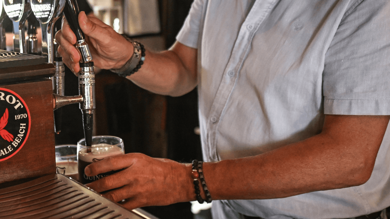 A bartender fills a glass of beer.