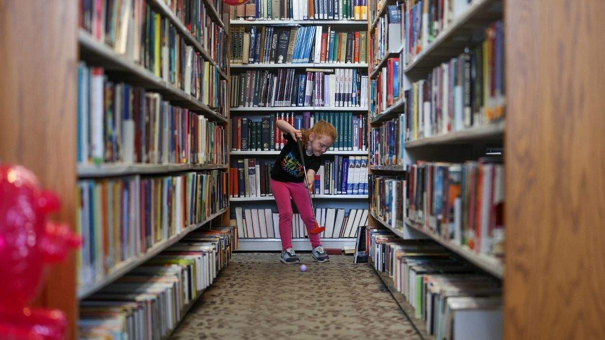 a child playing mini golf in library shelves