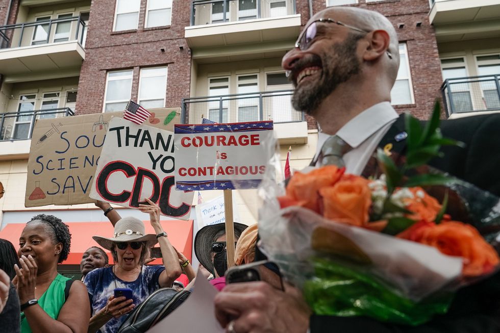 a crowd of supporters cheer for Demetre Daskalakis after his resignation from the CDC