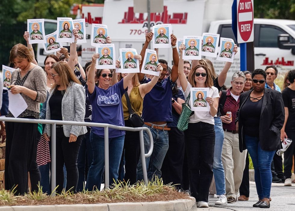 A crowd of supporters holding images of former CDC employees Dan Jernigan and Deb Houry and Demetre Daskalakis