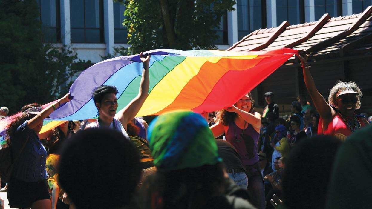 a group of people carry a large rainbow pride flag during a parade