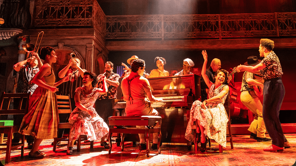 A group of people gathered around a piano player with a spotlight on him