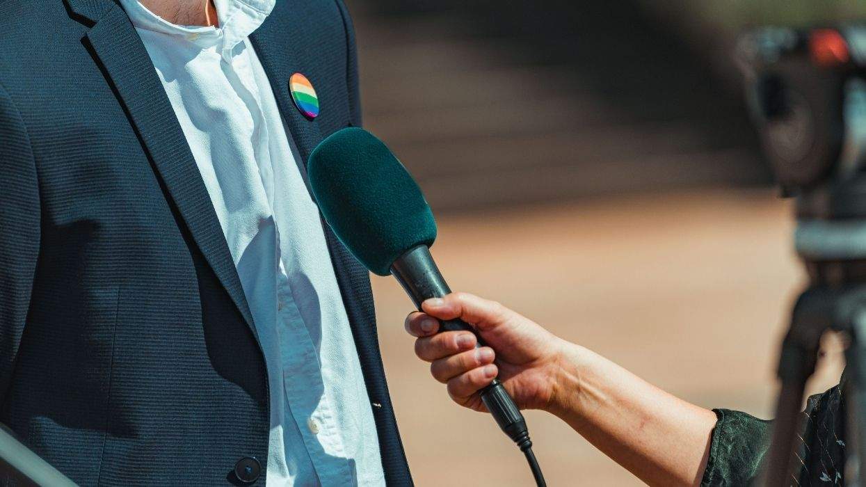a journalist interviewing somebody with a rainbow pin
