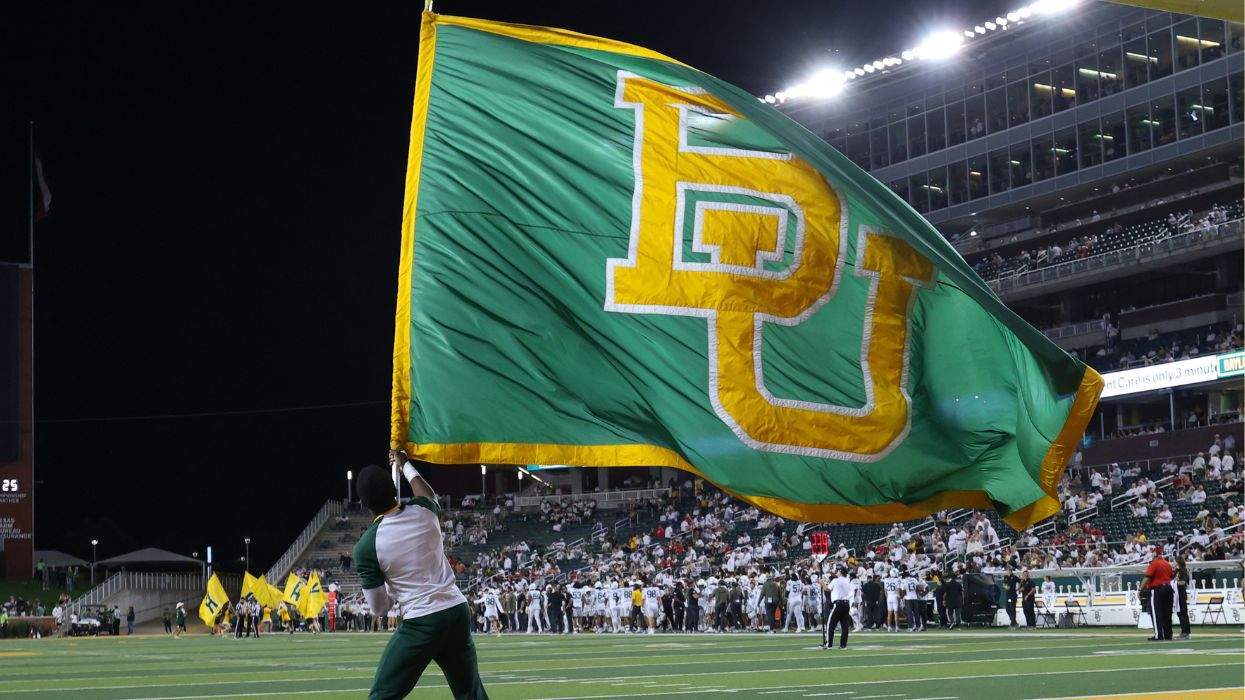 A large flag with the Baylor University logo is waved on the football field