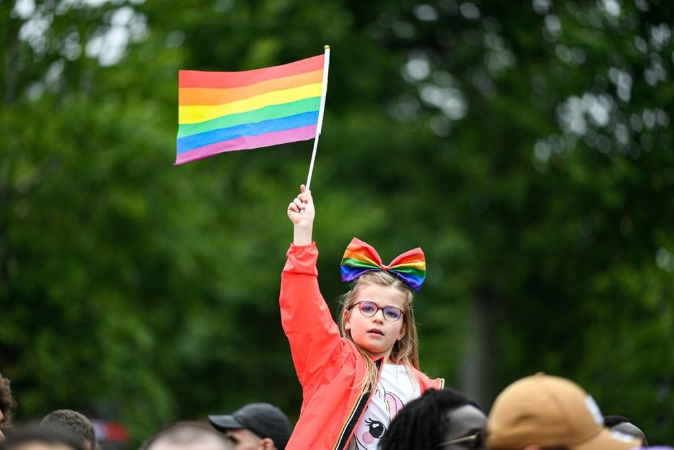 A little girl waving a rainbow flag