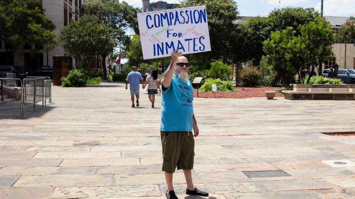a man with a sign that reads compassion for inmates