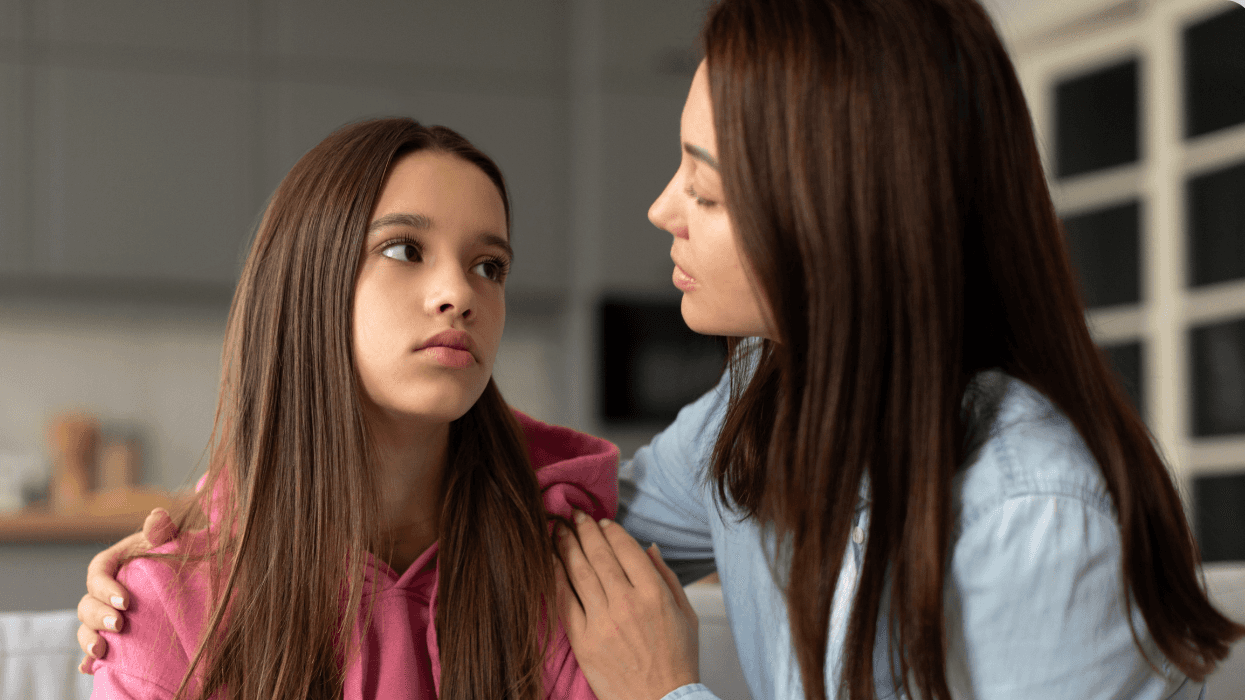 A mother speaks with her teenage daughter, who looks upset, during a serious conversation at home