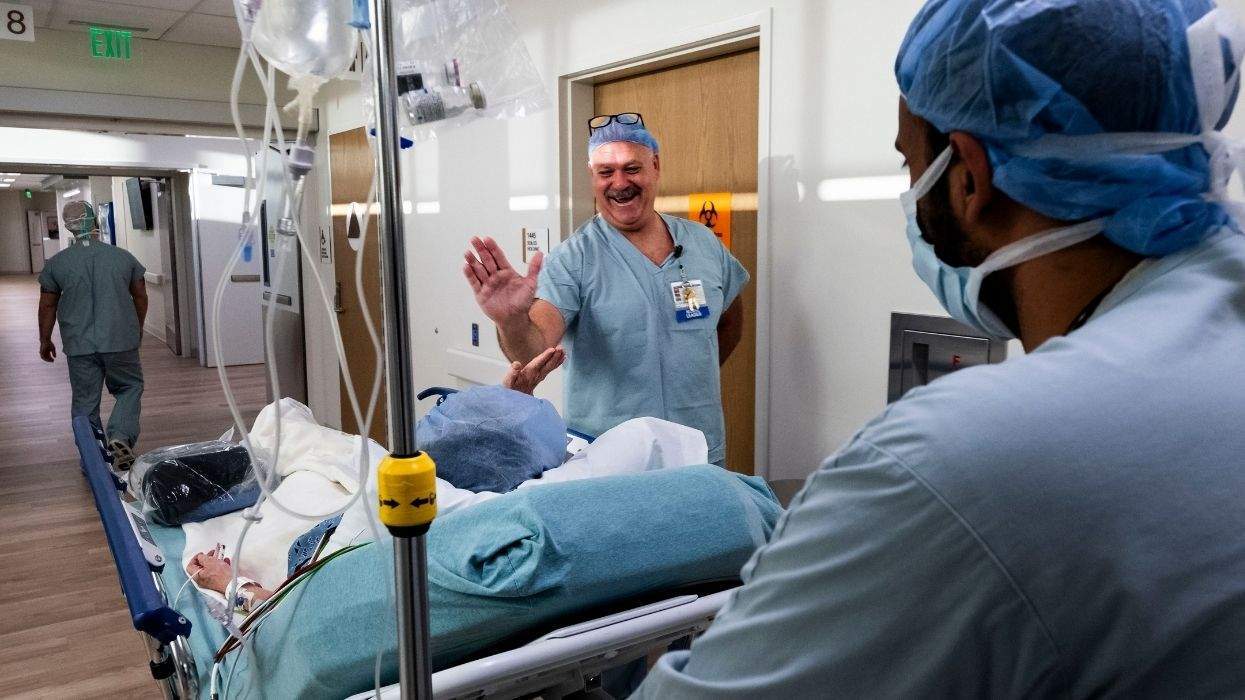 a patient high-fiving a medical provider while being pushed on a medical stretcher
