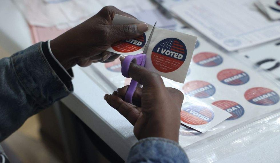 a person cutting an i voted sticker off a sheet with scissors