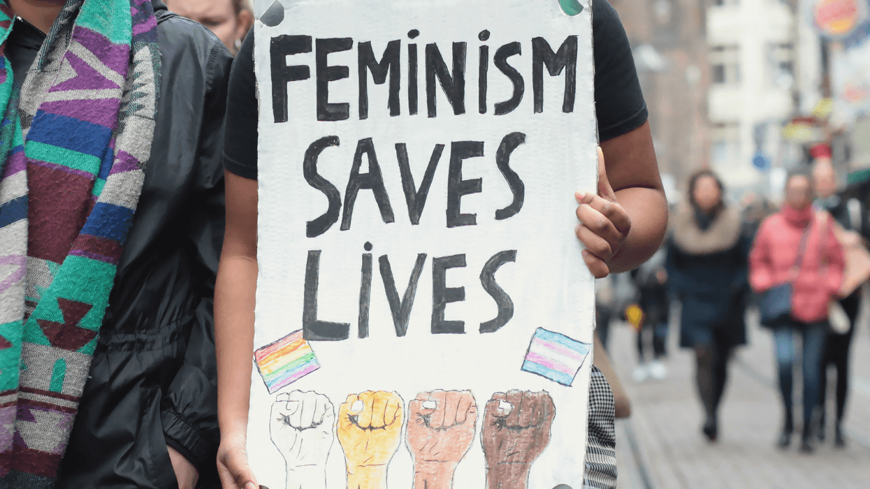 A person holds a “Feminism Saves Lives” sign during a street protest.
