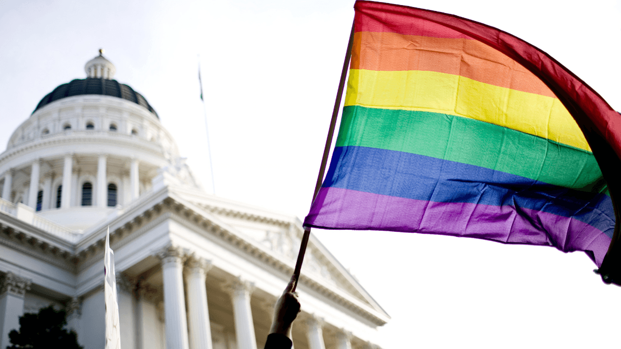 A rainbow LGBTQ+ Pride flag is raised outside of the California statehouse.