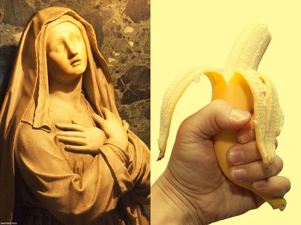 a religious statue and a half peeled banana in hand