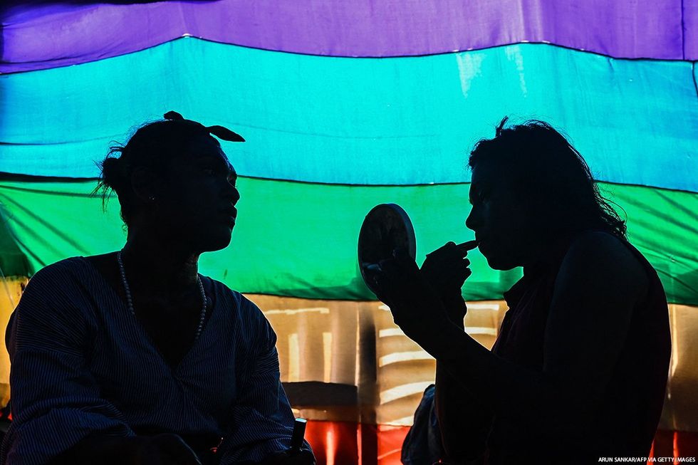 A silhouette of people before a pride flag.