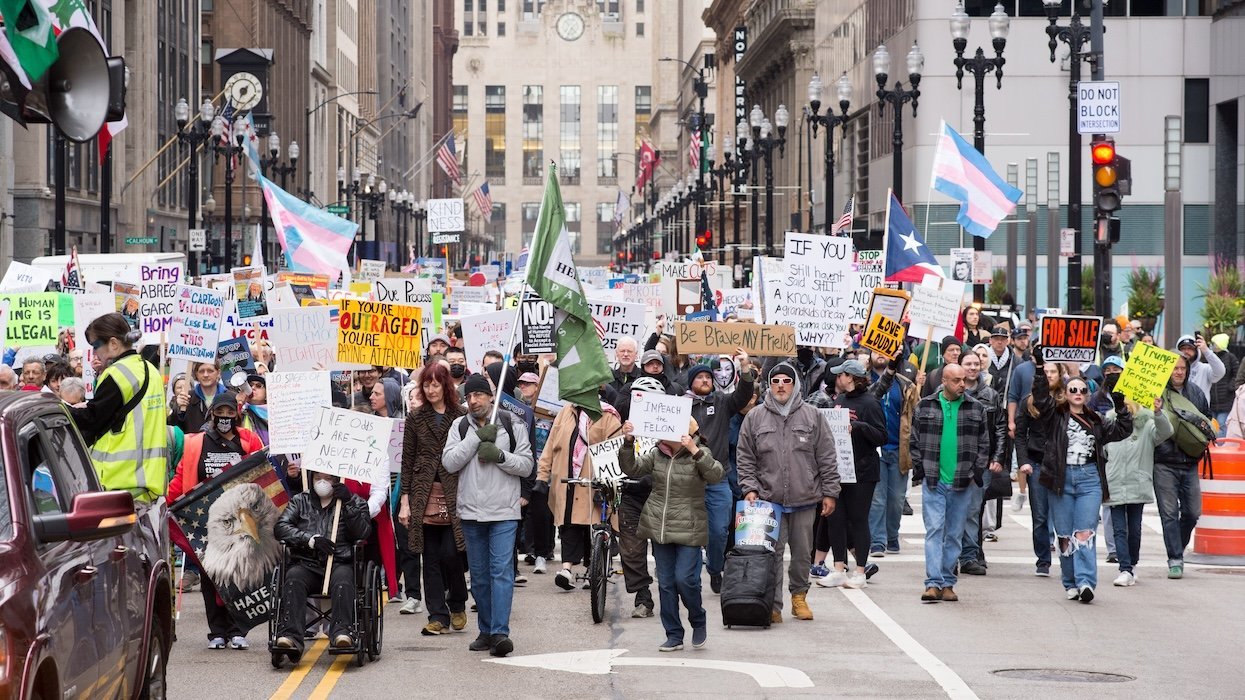 A street of people in Chicago holding different placards supporting trans rights, immigrants, and more.