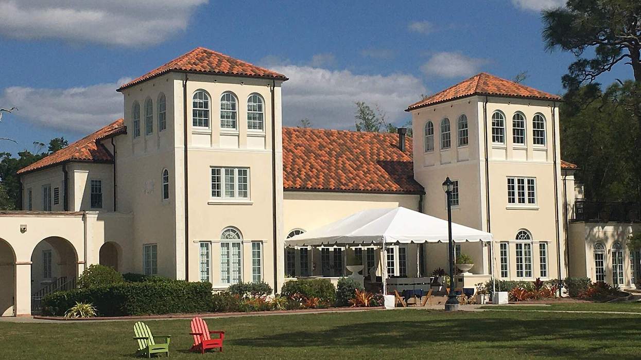 A white building with red roofing sits in a sunny lawn.