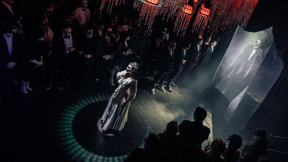 A woman standing in the middle of a masked audience