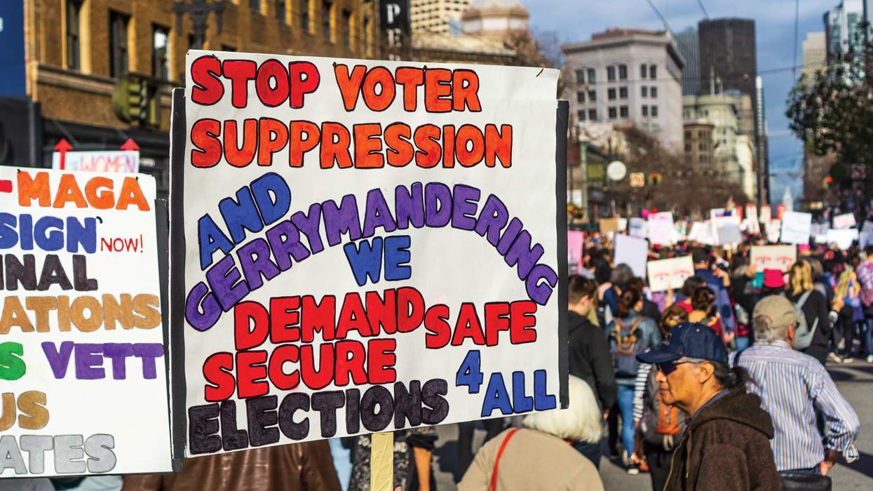 A Women’s March participant holds a sign referencing voting suppression and gerrymandering while marching on Market Street in downtown San Francisco.