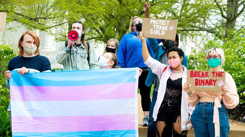 Activists in MIssouri holding signs and flags in support of transgender rights.