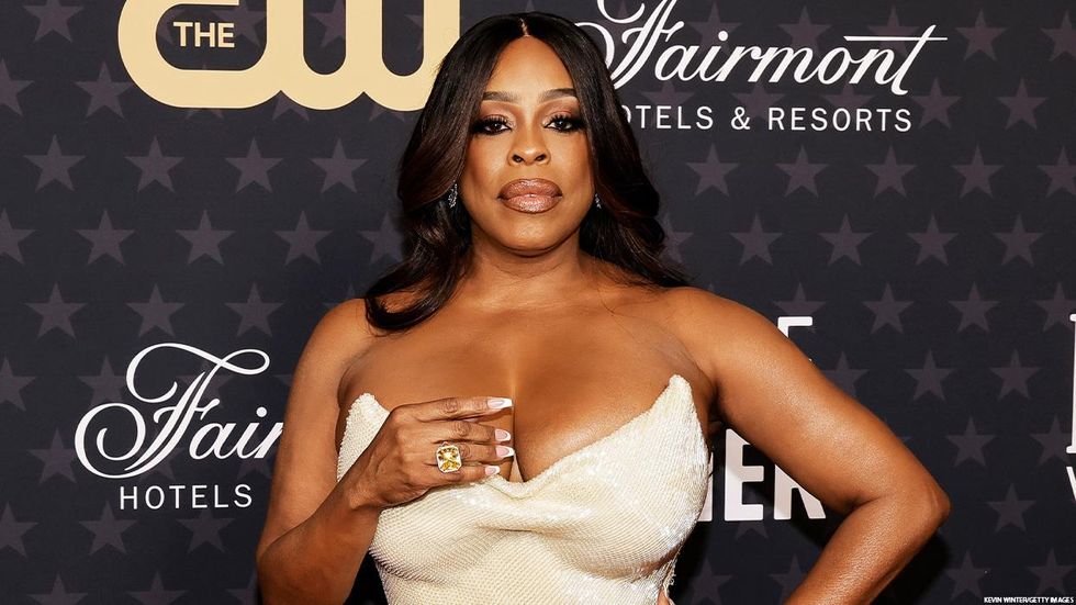 Actress Niecy Nash in front of a step and repeat screen sponsored by The CW and Fairmont Hotels