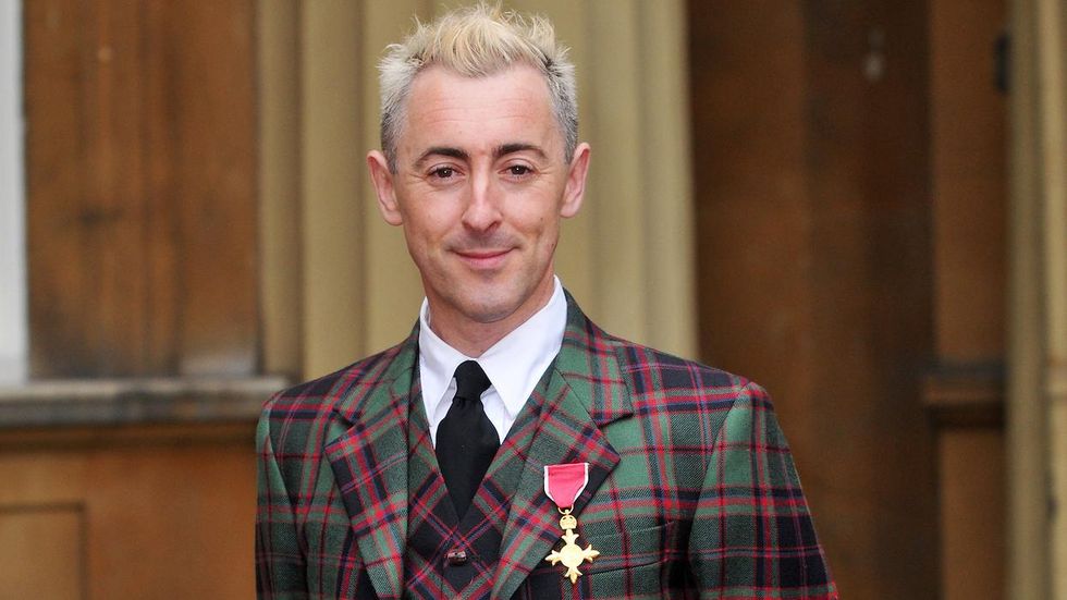Alan Cumming in a suit with this OBE award pinned to it