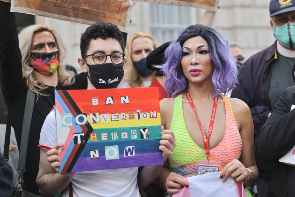An activist holding a sign that reads 'Ban conversion therapy now' during the demonstration.