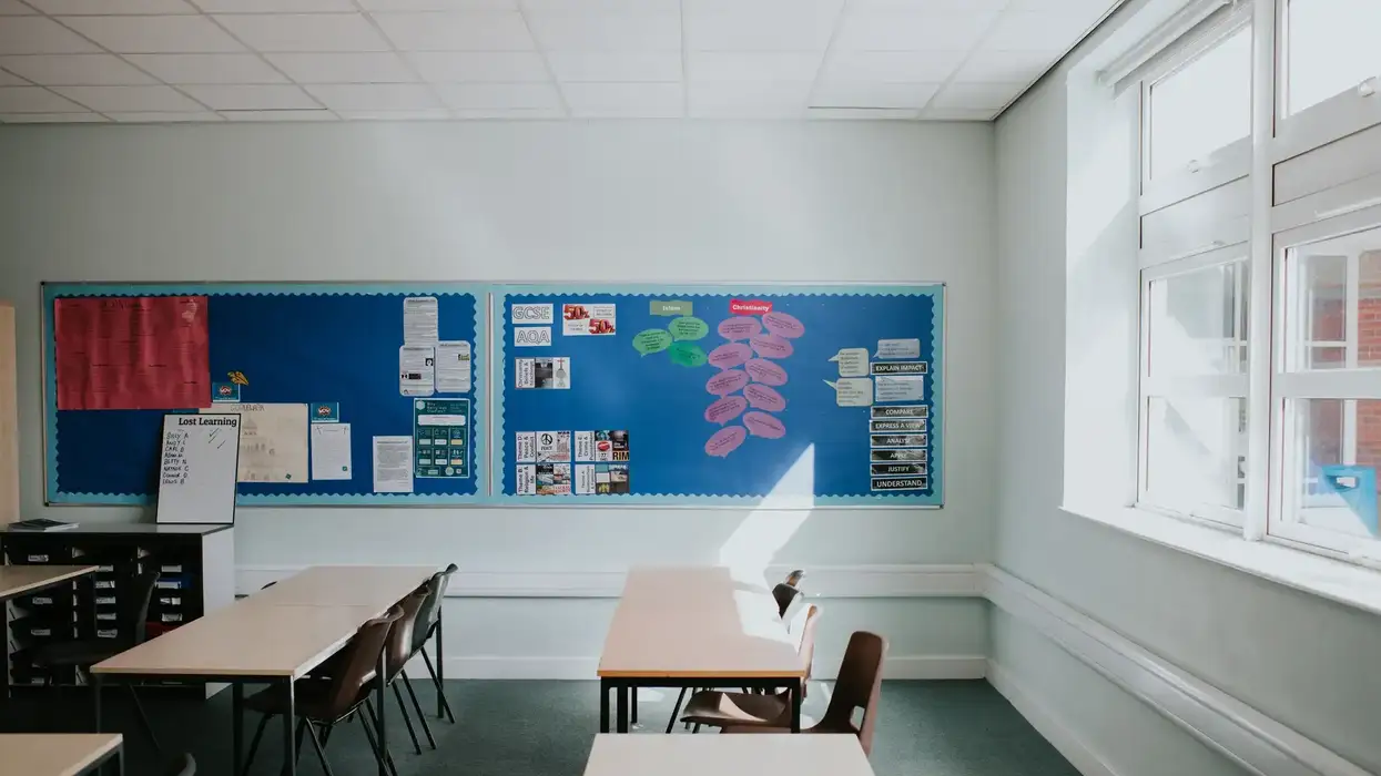 An empty classroom with desks, chairs, and educational posters displayed on bulletin boards.