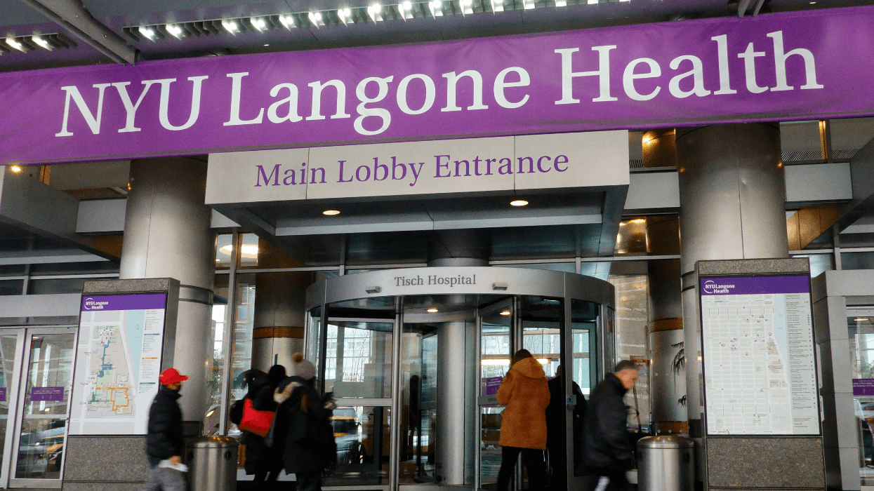 An entrance to a hospital displays large purple banners and a revolving door that reads "Tisch Hospital."