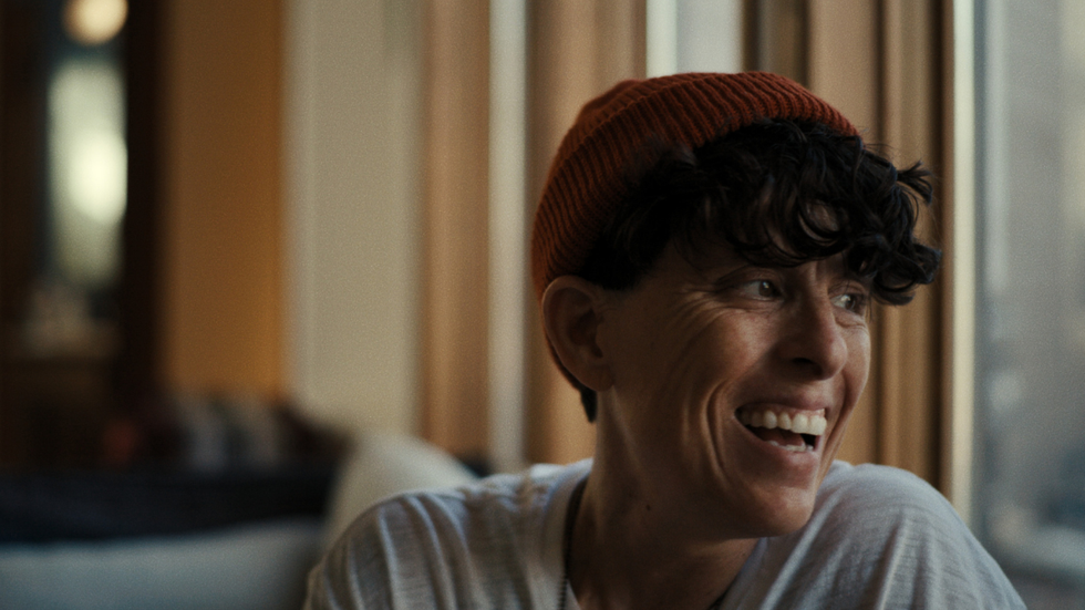 Andrea Gibson smiling and looking out a window