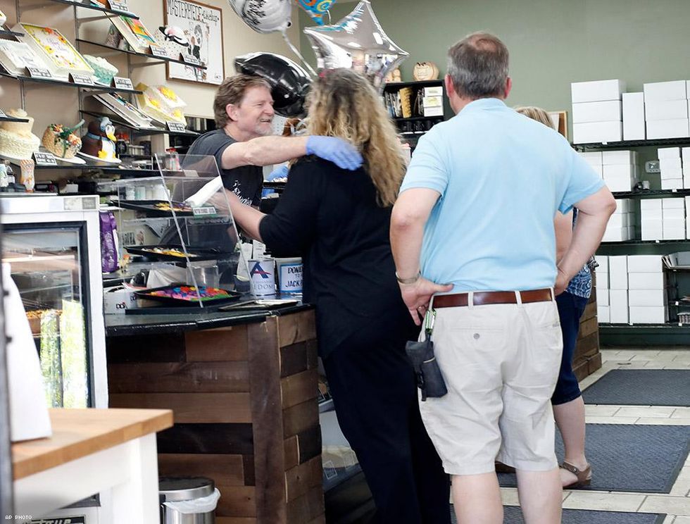 Baker Jack Phillips, owner of Masterpiece Cakeshop, left, hugs Ann Sewell as she comes into his shop after the Supreme Court ruled in his favor.