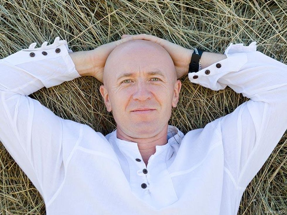 bald man in white shirt laying in the grass