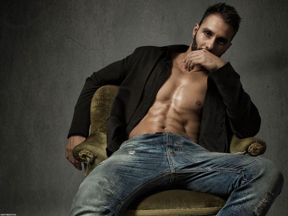 bearded man in green chair with short open wearing jeans