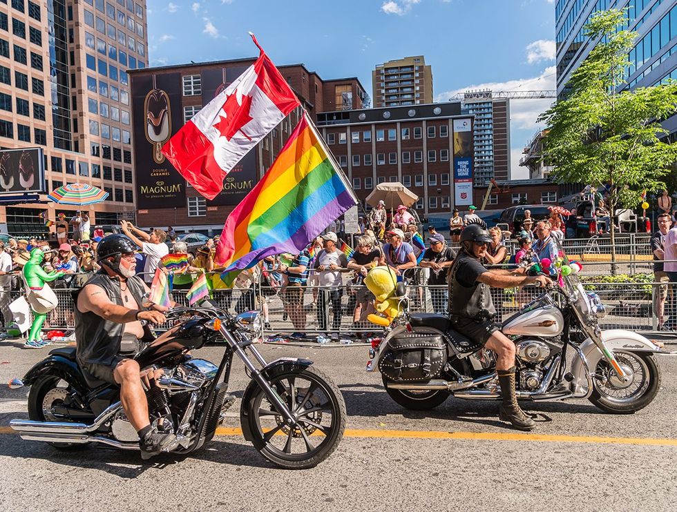 bikers on motorcycles at 2016 Toronto LGBTQIA Pride Parade with gay rainbow and canadian flags