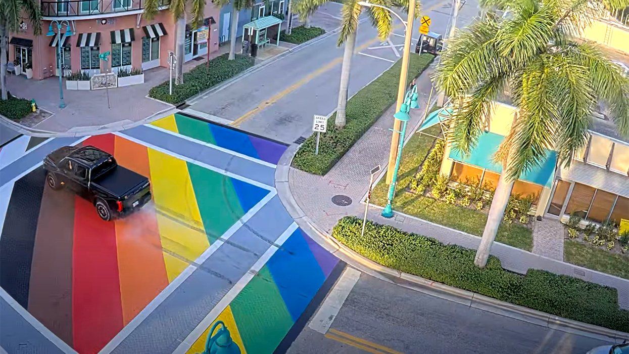 black pickup truck seen spinning wheels to mark up LGBTQIA pride rainbow street intersection in Florida