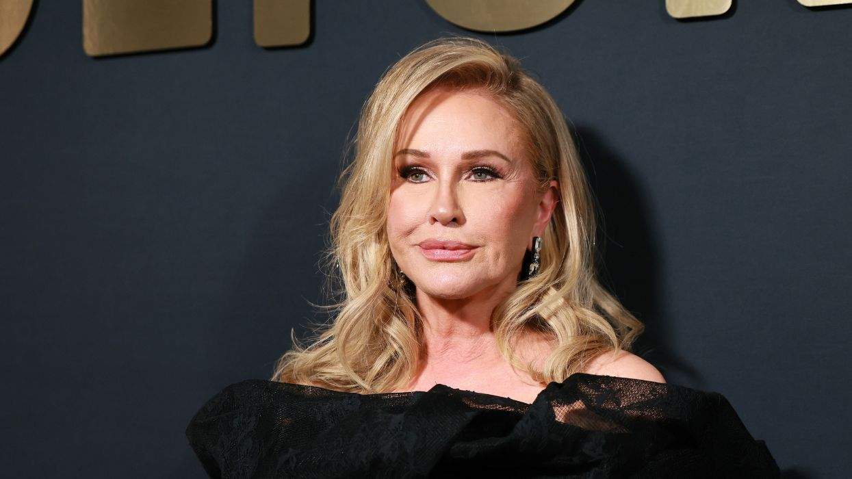 Blonde woman in elegant black outfit against a dark background with gold lettering.