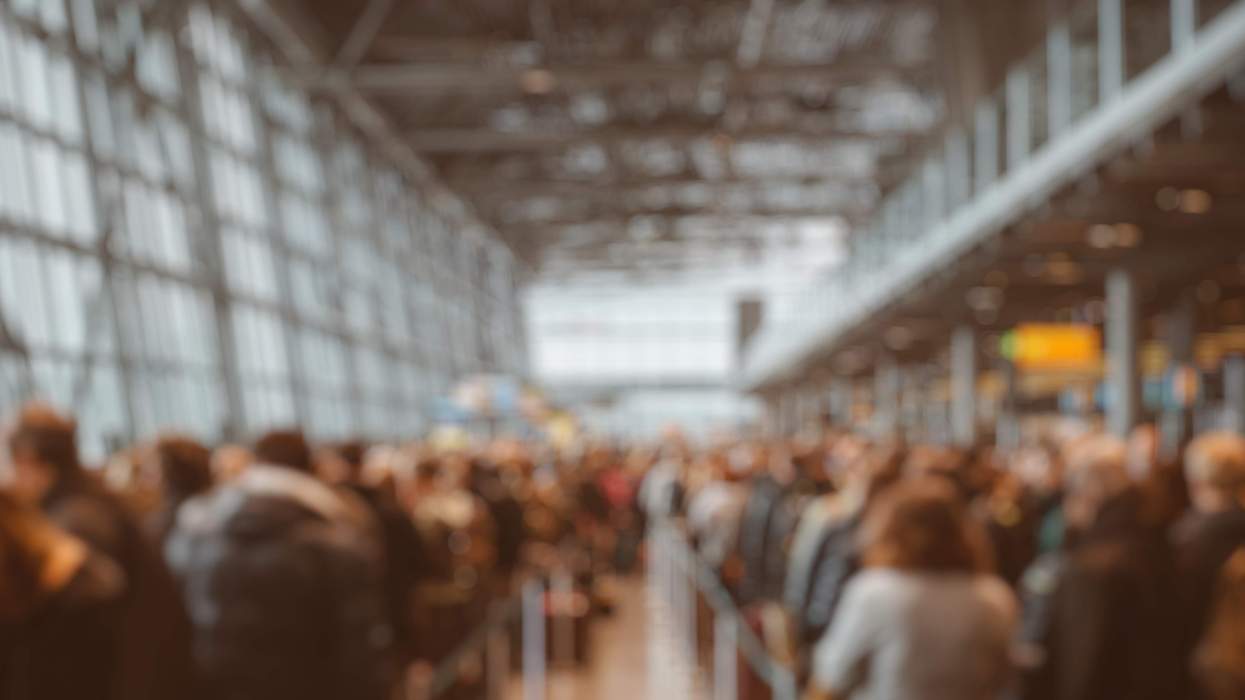 Blurred crowd of travelers moving through a busy airport terminal
