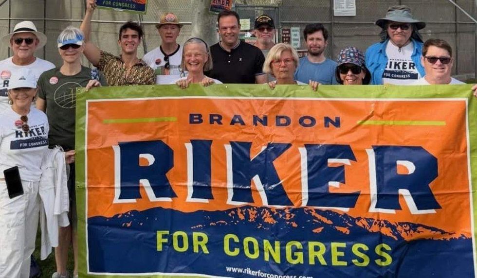 brandon riker behind a banner of his name "For congress" with volunteers