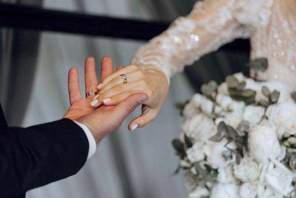 Bride and Groom holding hands with wedding rings
