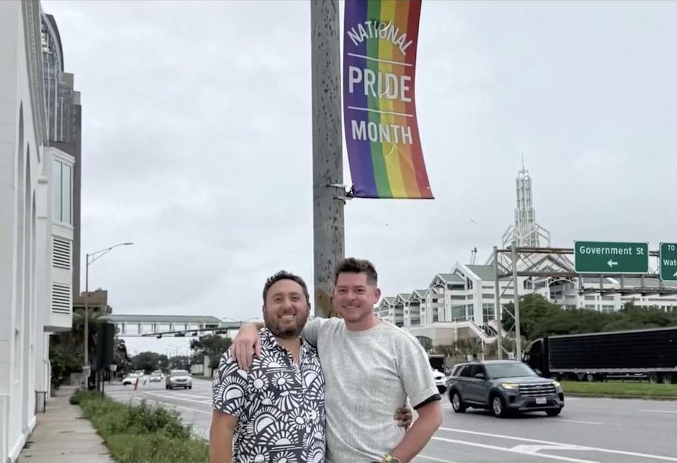 Bryan Fuenmayor and his husband stand proudly in front of one of their Pride month banners