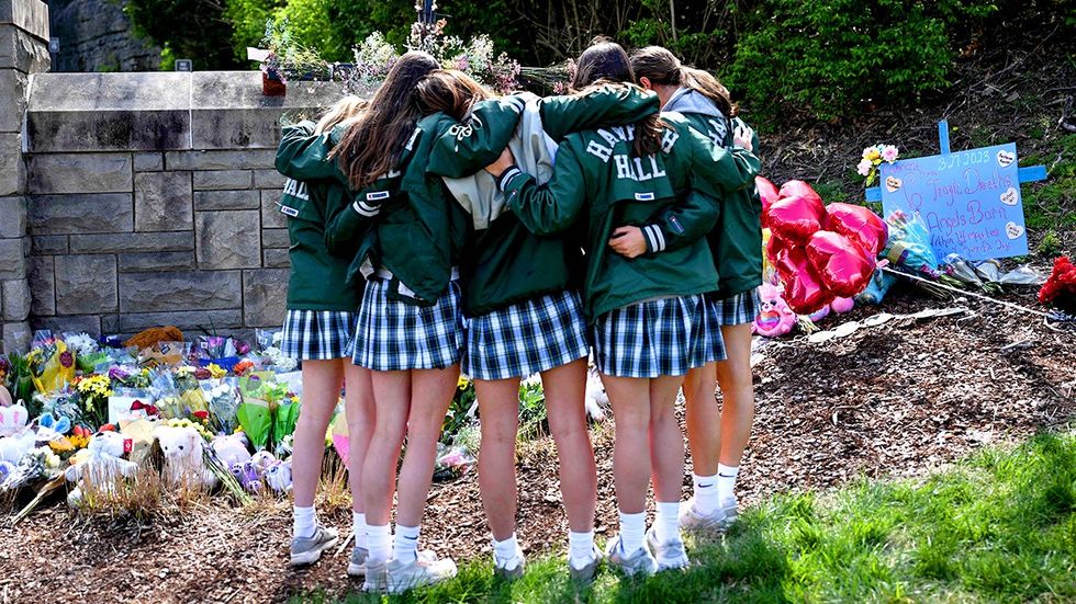 Catholic schoolgirl students embrace makeshift memorial school shooting victims Covenant Presbyterian Church Nashville Tennessee