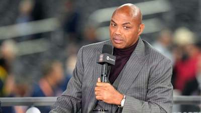 Charles Barkley in a gray suit holding a microphone with TNT Sports logo.
