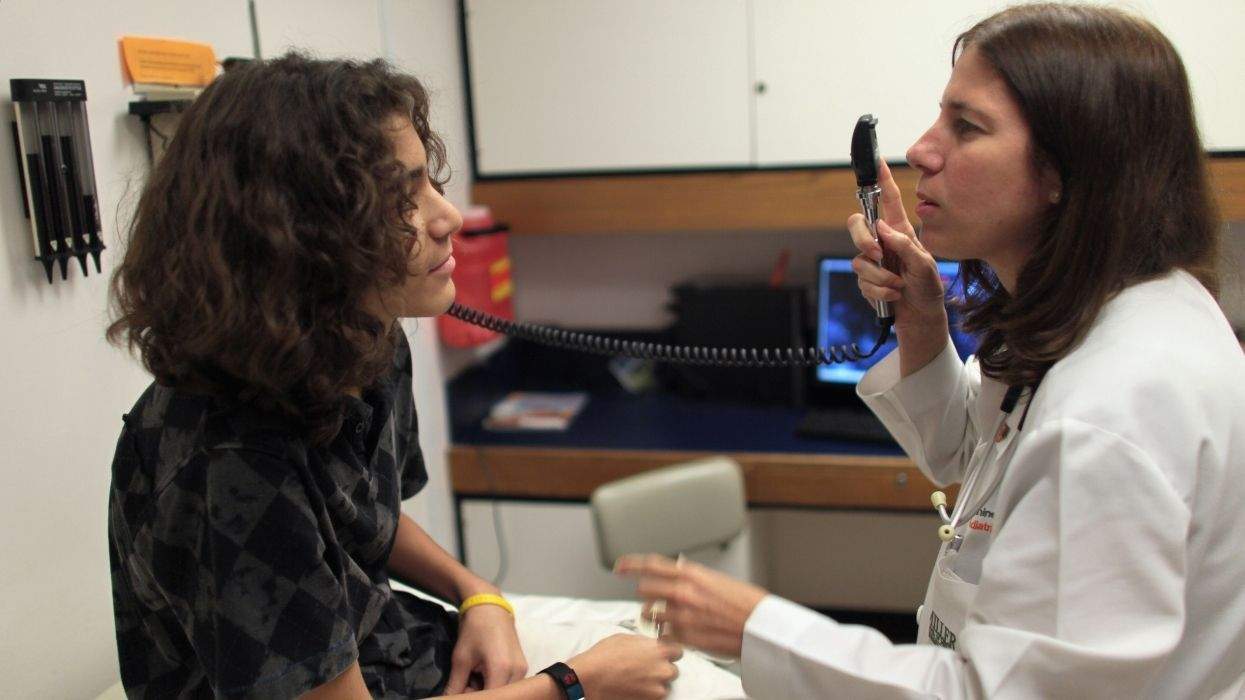 child siting on a docor's exam table with the doctor beginning an examination with a light tool