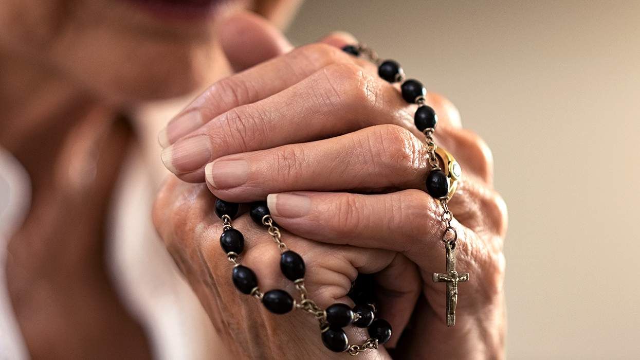 closeup of womans hands holding christian rosary prayer beads
