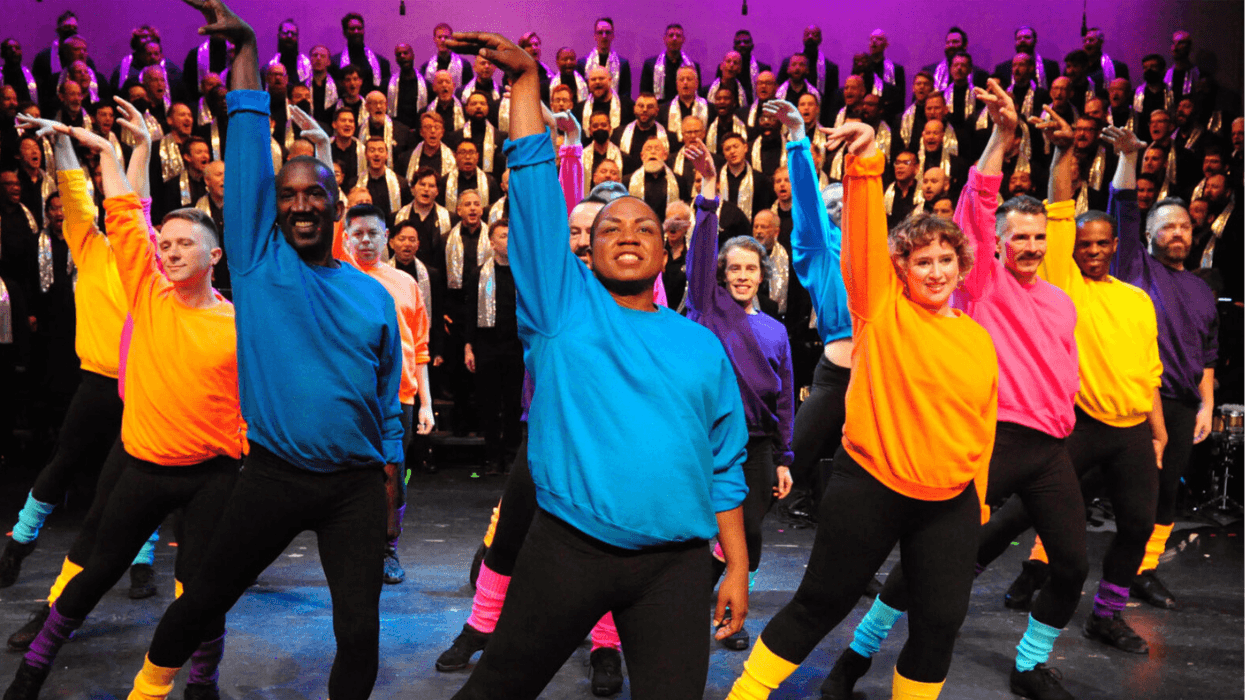Colorfully dressed performers dance onstage in front of members of the Gay Men’s Chorus of Washington, DC
