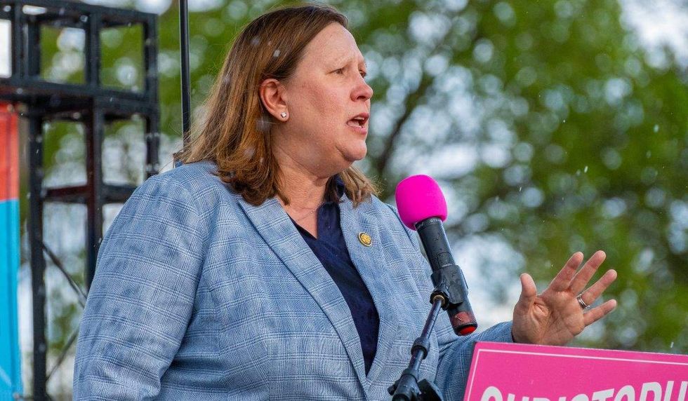 congresswoman julie johnson standing on a stage with a microphone before her