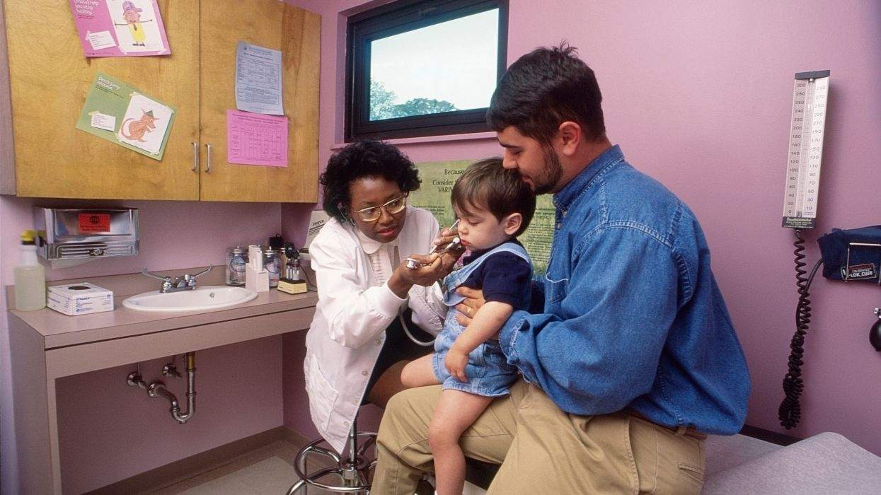 doctor examining a toddler with a parent holding the child