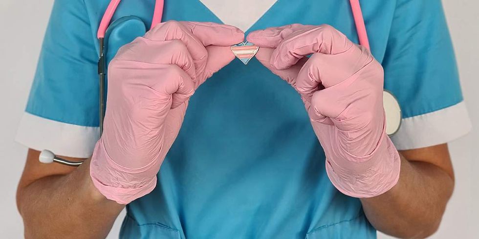 doctor holding a trans flag pin