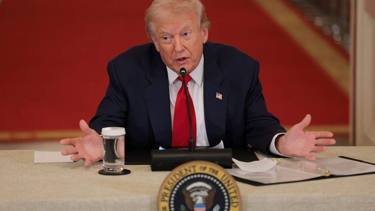donald trump sitting at a table with the seal in front of him and a glass of water with a binder and a microphone