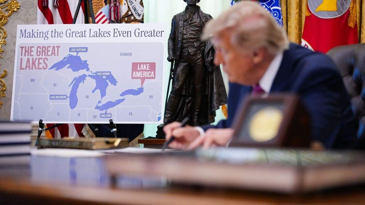 donald trump writing with a sharpie next to a sign that indicates lake ontario is now lake america