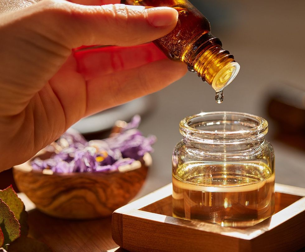 dripping aromatic essential oil for a spa beauty treatment into a bigger jar