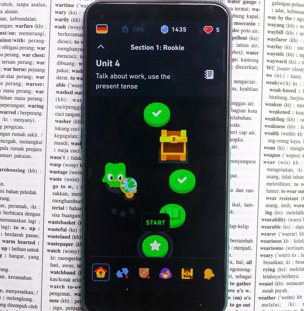 Duolingo app foreign language learning app lesson on cell phone over English dictionary page